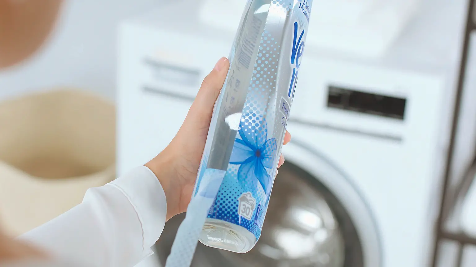 A person seen from behind removes a thin film jacket from a Vernel bottle.