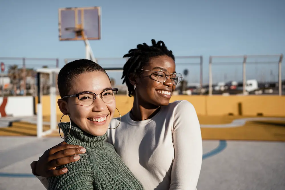 duas mulheres abraçadas num campo de basquetebol 