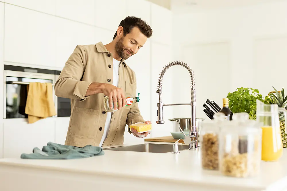 Homem na cozinha a lavar a loiça